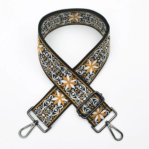 Close-up of yellow and white floral embroidery on a wide crossbody bag strap with metal hook