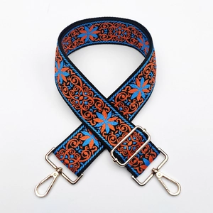 Close-up of Bohemian embroidered bag strap with orange and blue floral pattern and gold clips