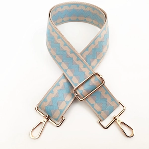 Detail of wide adjustable shoulder strap with blue geometric pattern and gold buckles