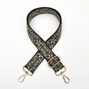 Close-up of ethnic floral embroidery strap with golden metal lobster clasps for bags