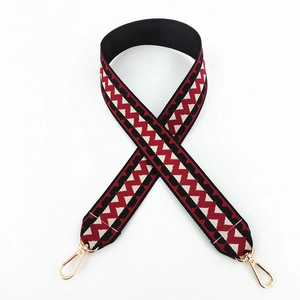 Detail of red and black geometric wave pattern woven bag strap with gold metal hooks
