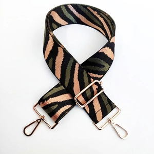 Macro shot of zebra pattern woven bag strap with polished rose gold lobster clasps