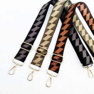 Detail of adjustable wide canvas bag straps with geometric zigzag patterns and gold hooks