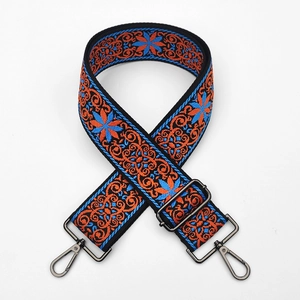 Close-up of ethnic floral embroidery on a wide bag strap with gunmetal black hooks