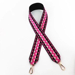 Close-up of bohemian pink and black geometric woven wide shoulder strap with gold clasps