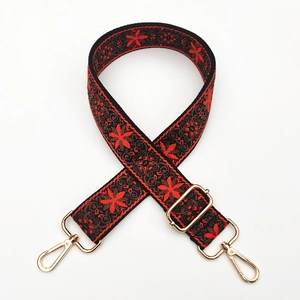 Close-up of ethnic red and black woven bag strap with golden metal lobster clasps