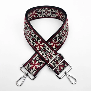 Detail of ethnic floral jacquard bag strap with silver metal hooks and thick woven texture