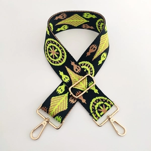 Détail d'une bandoulière large tissée avec broderie ethnique et attaches dorées en métal