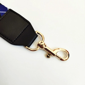 Detalle de correa de tela azul para bolso con cierre dorado y cuero negro