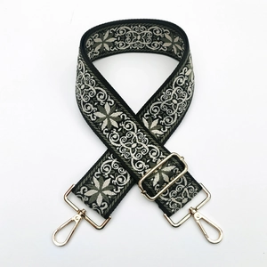 Detail of wide ethnic embroidered bag strap with floral patterns and gold metal clasps
