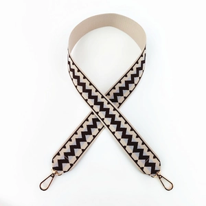 Close-up of woven wide bag strap with black and grey wave pattern and gold metal hooks