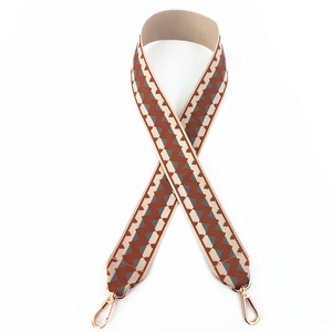 Detail of wide woven strap with brown geometric patterns and gold swivel metal hooks