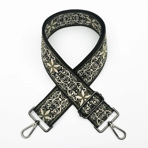 Detail of adjustable wide jacquard strap with dark metal hooks and ethnic floral pattern