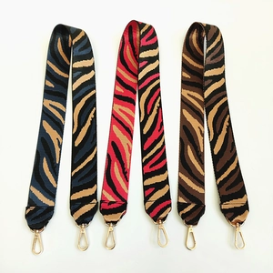 Detail view of woven nylon shoulder straps with zebra patterns and gold metal lobster clasps