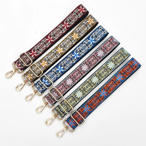 Detail of ethnic embroidered bag straps with colorful floral patterns and gold metal buckles