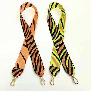 Close-up of zebra pattern wide nylon shoulder straps with gold metal swivel hooks