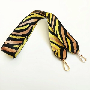 Detail of colorful woven nylon shoulder strap with gold-tone metal lobster clasps and hardware