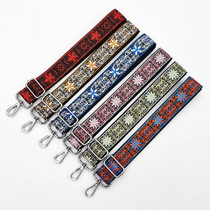 Detail view of ethnic embroidery bag straps with floral patterns and silver metal hooks