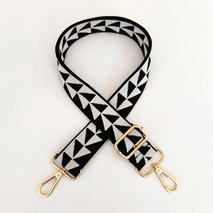 Detail of adjustable black and white geometric woven strap with gold metal lobster clasps