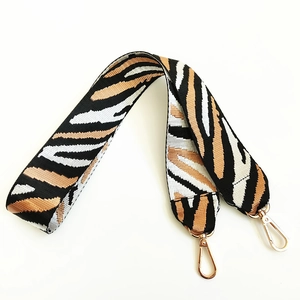 Detail of zebra pattern nylon strap with polished gold lobster clasps for handbags
