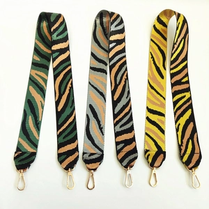 Close-up of wide nylon shoulder straps with animal print patterns and gold metal lobster clasps