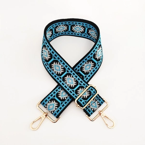 Close-up of ethnic jacquard bag strap with blue geometric patterns and gold metal clips