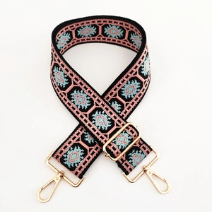 Close-up of ethnic jacquard purse strap with pink geometric patterns and gold metal hooks
