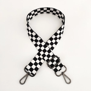 Detail of adjustable black and white checkerboard woven bag strap with gunmetal hooks