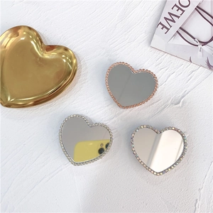 Close-up of heart-shaped mirror phone grips with sparkling rhinestones in three colors