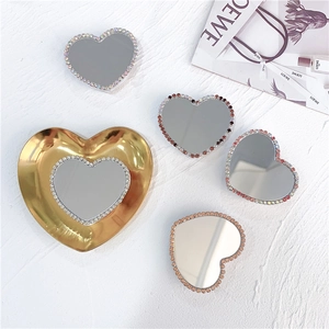 Detail view of heart-shaped rhinestone mirror phone grips on a gold heart tray