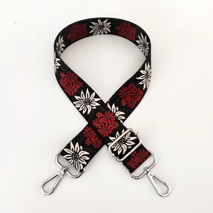 Detail of adjustable ethnic style bag strap with red floral print and silver metal hooks