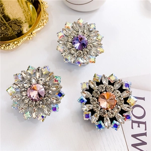 Close-up of luxury flower-shaped rhinestone phone stands in purple, pink, and amber gems