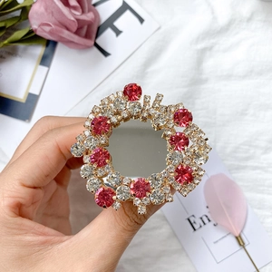 Detail of a luxury round mirror phone grip with sparkling red and clear rhinestones