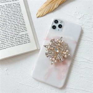 Dettaglio supporto telefono fiocco di neve con strass e perle su cover marmo
