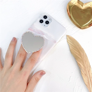 Detail of rhinestone heart mirror phone socket on white marble case from a 45-degree angle