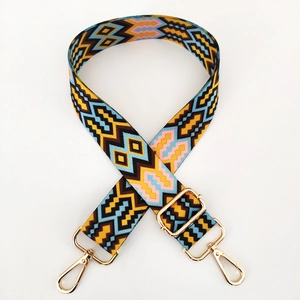 Detail of adjustable ethnic style bag strap with colorful geometric weave and gold buckles