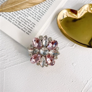 Detailed close-up of pink and clear crystal flower phone grip on white textured surface
