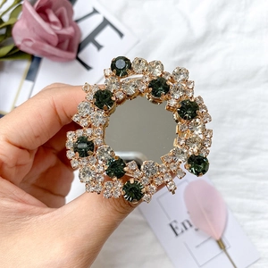 Close-up of a sparkling mirror phone grip with emerald green rhinestones and gold base