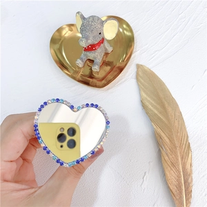 Close-up of heart-shaped phone grip with blue rhinestones and integrated mirror