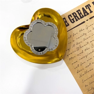 Close-up of golden heart-shaped mirror phone stand with rhinestone flower accents