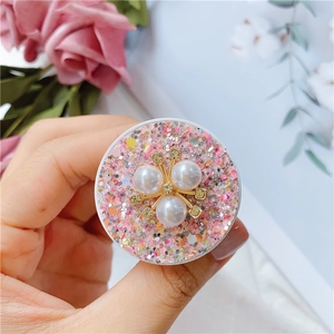 Nahaufnahme einer glitzernden rosa Handyhalterung mit Perlen, von Hand präsentiert
