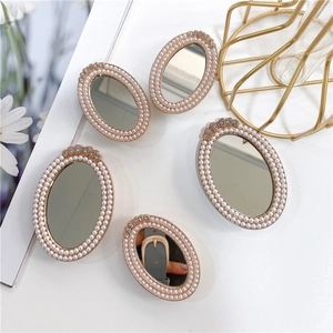 Close-up of pearl-rimmed oval mirror phone grips with sparkling rhinestone accents