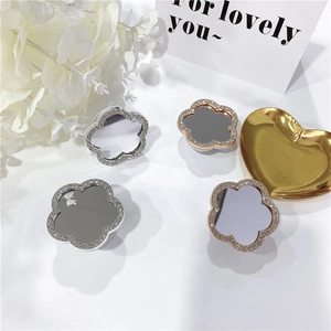 Close-up of sparkling floral phone grips with rhinestones and mirrors on gold heart tray