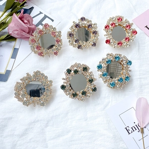Macro shot of six assorted rhinestone mirror phone grips on white fabric with rose petals