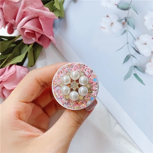 Nahaufnahme der rosa Glitzer-Handyhalterung mit weißen Perlen und goldener Blumenmitte