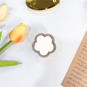 Detailed view of flower-shaped phone grip with sparkling rhinestones and white mirror surface