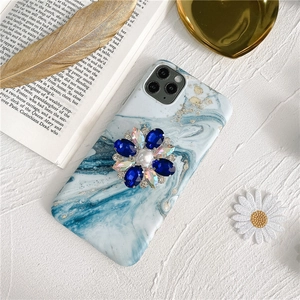 Detail of blue marble phone case with a crystal flower stand and centered white pearl