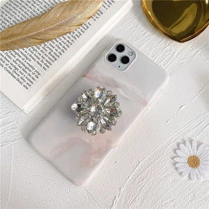 Macro detail of luxury crystal flower pop socket on marble pattern phone case