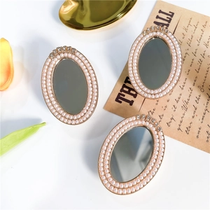 Macro shot of oval vintage mirror phone grip with faux pearl inlay and rhinestone accents