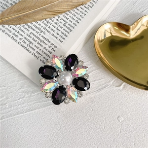 Close-up of a floral jewelry phone grip with crystal petals and a central pearl accent